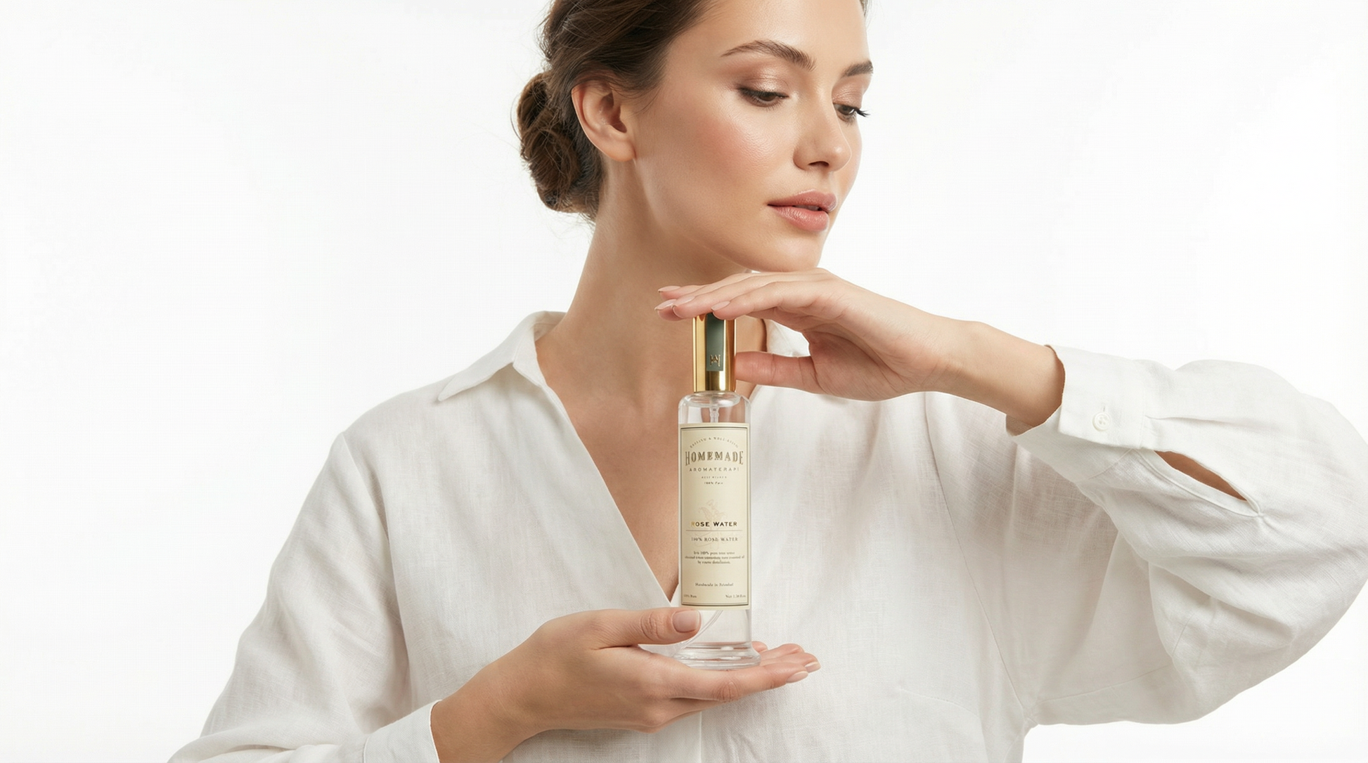 Woman in a white shirt holding a bottle of HomeMade Aromaterapi 100% Pure Rose Water against a light background.